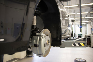 The car on the lift prepared to repair. Details of the brake system. Background interior repair shop.