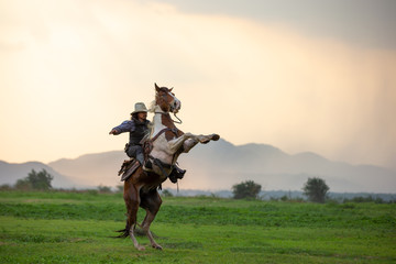 cowboy riding horse against sunset 
