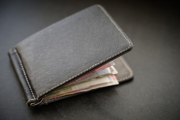 Wallet with money on dark background.