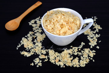 Cornflakes in coffee cup on a dark wooden background and copy