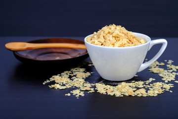 Cornflakes in coffee cup on a dark wooden background and copy
