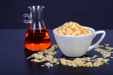 Cornflakes in coffee cup on a dark wooden background and copy