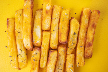 Baked potatoes with aromatic herbs on a yellow background. The concept of fast food, unhealthy food. French fries. Minimalism, flat lay, top view, place for text.