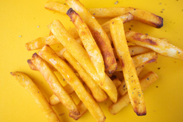 Baked potatoes with aromatic herbs on a yellow background. The concept of fast food, unhealthy food. French fries. Minimalism, flat lay, top view, place for text.