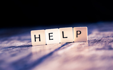 Help word made of tiles on dark wooden background