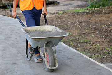 Worker carries a wheelbarrow with the ground. Man with cargo, concept of earthworks, digging, construction of the road, landscaping