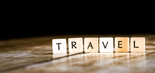 Travel word made of tiles on dark wooden background