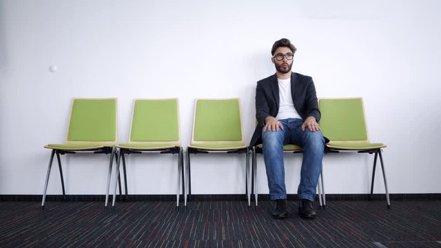 Impatient and stressed young man waiting for job interview in hallway
