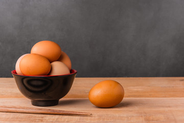 close-up of chicken eggs in black bowl on wooden table