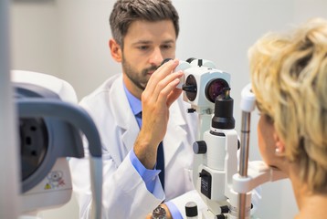 Closeup of doctor examining senior womans eye at hospital