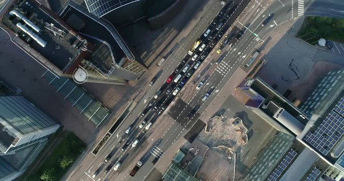 Aerial top down view of junction with cars and traffic at the morning rush hour during summer sunny day. Drone flying above filming straight down and indirect following the street. Helsinki Finland