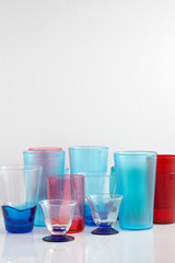 Group of various color glass on white table with a blank space for a text, glass on white background