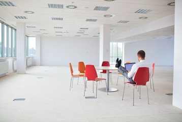 Rear view of young businessman using laptop at new office