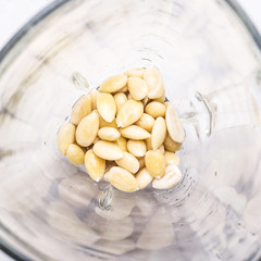 Peeled almonds in a glass bowl of a blender for making milk