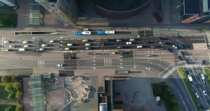 Aerial top down view of junction with cars and traffic at the morning rush hour during summer sunny day. Drone flying above from right to left filming straight down the street. Helsinki Finland
