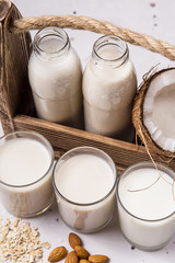 Vegan milk from coconut, oatmeal and almonds on a gray table