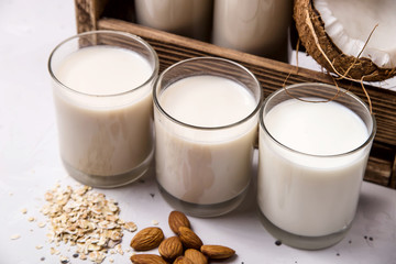 Vegan milk from coconut, oatmeal and almonds on a gray table