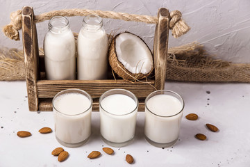 Obraz na płótnie Canvas Vegan milk from coconut, oatmeal and almonds on a gray table
