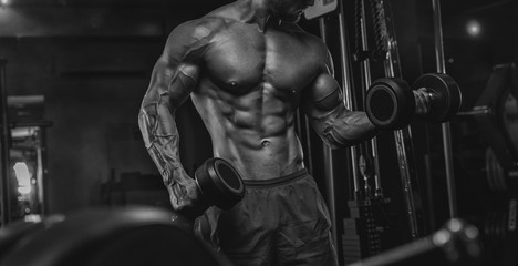 Fototapeta na wymiar Brutal handsome Caucasian bodybuilder working out training in the gym gaining weight pumping up muscles and poses fitness and bodybuilding concept