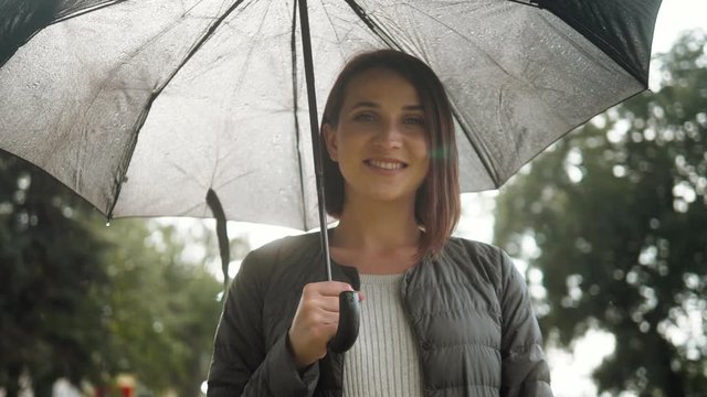 Portrait of smiling woman under umbrella in rain. Tourist girl under umbrella in rain