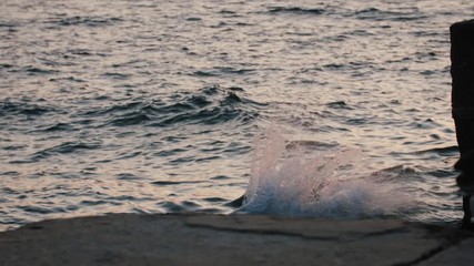 Young youman jumping from sea pier and doing frontflip during beautiful sunrise, slow motion