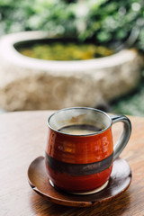 americano of Dark hot a coffee in red cup on wood table and filtre instagram vintage tone