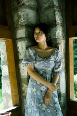 Portrait of beautiful young woman standing with old wall and windows in Chinese traditional garden