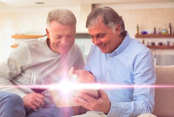 Smiling mature men using digital tablet while sitting at home