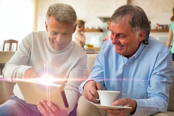 Smiling mature men using digital tablet while sitting at home