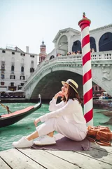 Foto op Plexiglas Rialtobrug vrouw zitten in de buurt van de rialtobrug in venetië, italië, kijken naar het grote kanaal met gondels