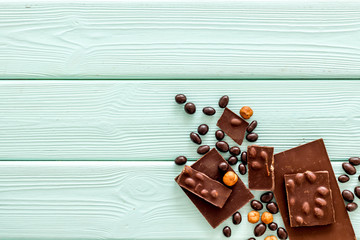 Different variety of chocolate and hazelnut on mint green wooden background top view space for text