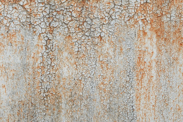Old metal rusted wall covered with cracked and partly peeled white paint. Grunge background and texture. Close-up