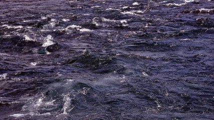 Water of a fast mountain river with rapids.