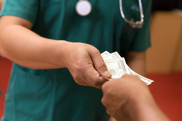 Doctor hand hold money in somewhere,hospital,clinic. Someone pay money,pay buy something for medical expenses or pay for corruption.