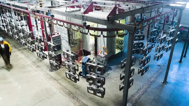 Timelapse conveyor line for painting metal products powder . On a moving line hanging rectangular body for electric tiles, waiting for hand painting in the shop