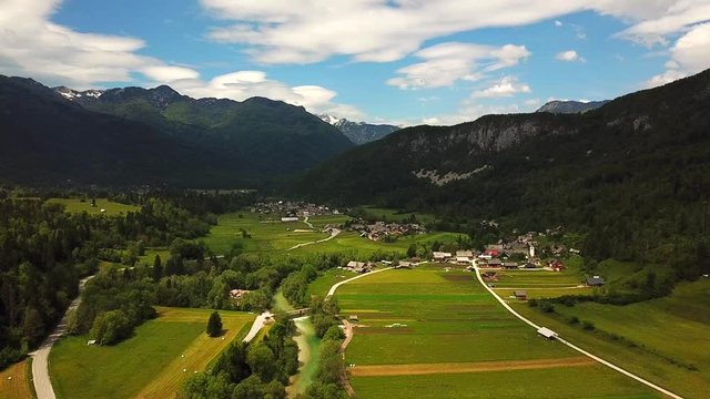 Rising drone shot of Bohinjska Bistrica, Slovenia, next to a river flowing, surrounded by mountains