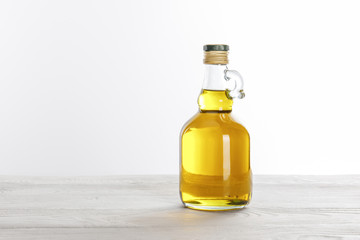 Transparent glass bottle of oil on white wooden table isolated on white