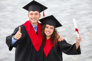 Happy students in bachelor robes outdoors