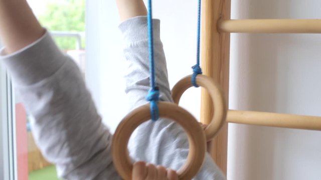 child uses gymnastic rings in muscle training