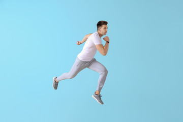 Running young man on color background