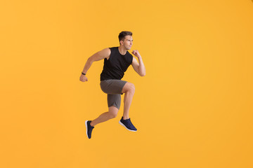 Fototapeta na wymiar Running young man on color background