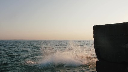 Group of young friends jumping and doing tricks from a pier into the sea during beautiful sunrise, slow motion