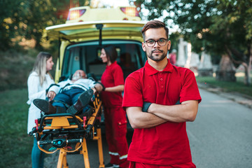 Emergency medical service at work. Paramedic is pulling stretcher with senior man with serious heart attack to the ambulance car. Help on the road. Drivers assistance concept. © hedgehog94