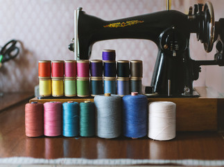 Vintage multicolor sewing threads on background of sewing machine, selective shallow focus, sewing supplies