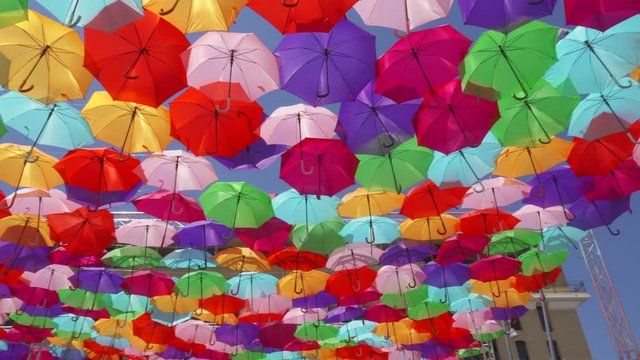 Top view of street decorated with multicolored umbrellas in Aix en Provence, France. Beautiful colorful parasols hanging in air above at sunny summer day