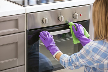 Woman cleaning oven in kitchen