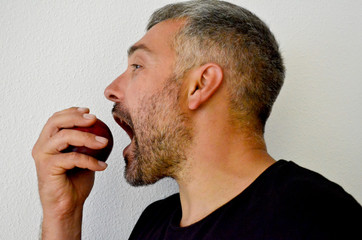 Obraz premium Man in profile about to eat a peach