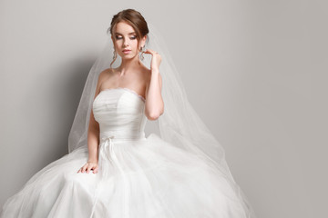 Fototapeta premium Portrait of beautiful young bride on grey background