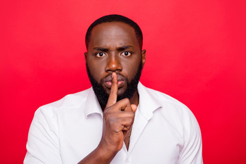 Dark skin guy begging to stop talking and keep silence wear white shirt isolated red background
