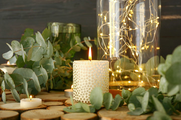 Beautiful burning candles with eucalyptus on table